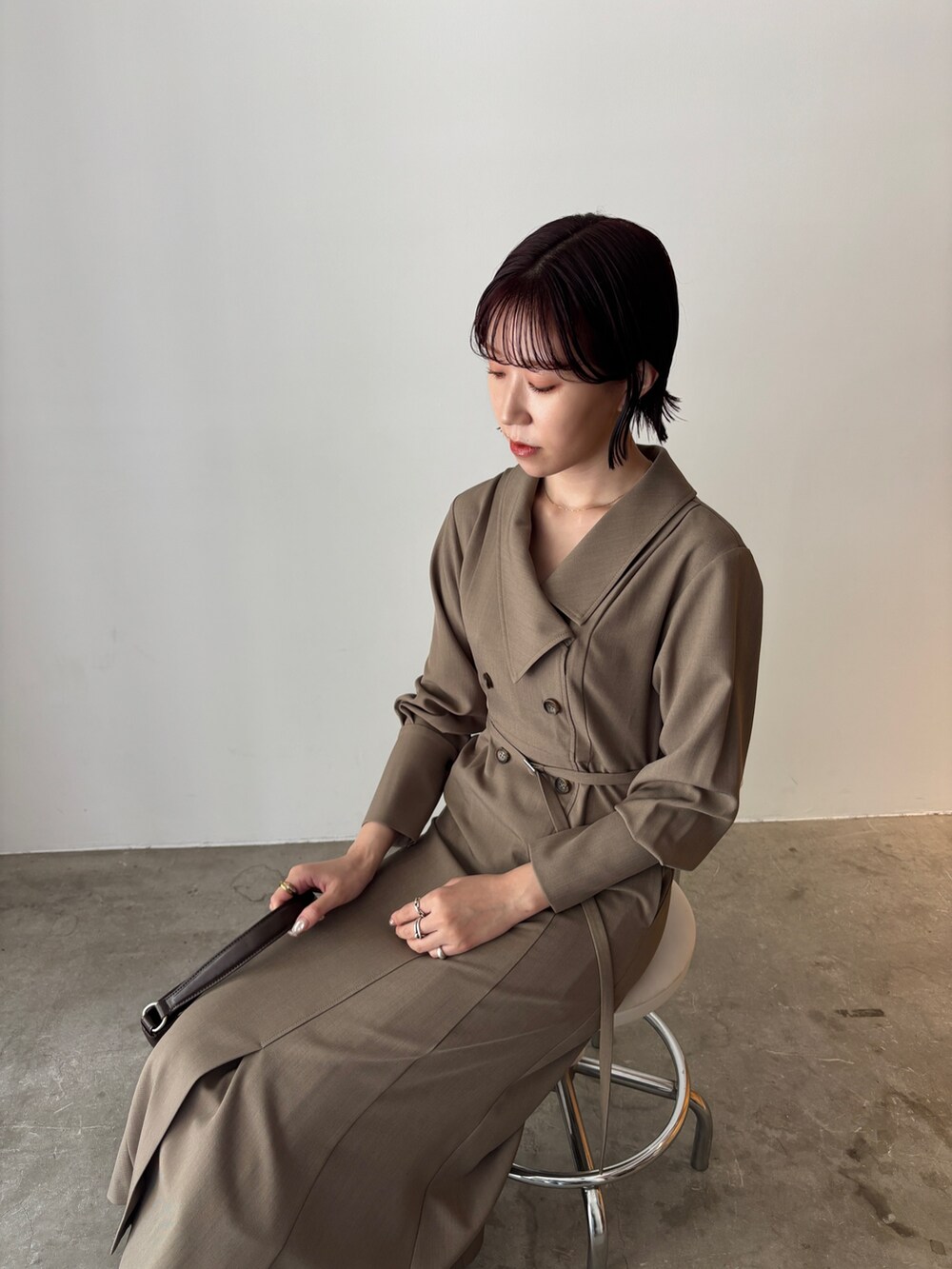 ホワイト系のワンピース、ブラウン系のハンドバッグ、ブラウン系のブーツを着用したレディースの秋コーディネートの6枚目の写真