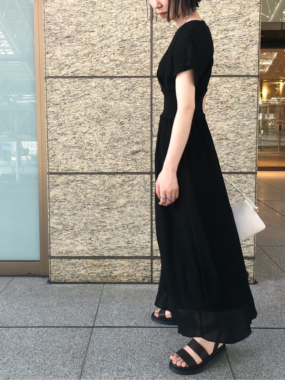 ブラック系のワンピース、ブラウン系のサンダル、シルバー系のブレスレットを着用したレディースの夏コーディネートの6枚目の写真