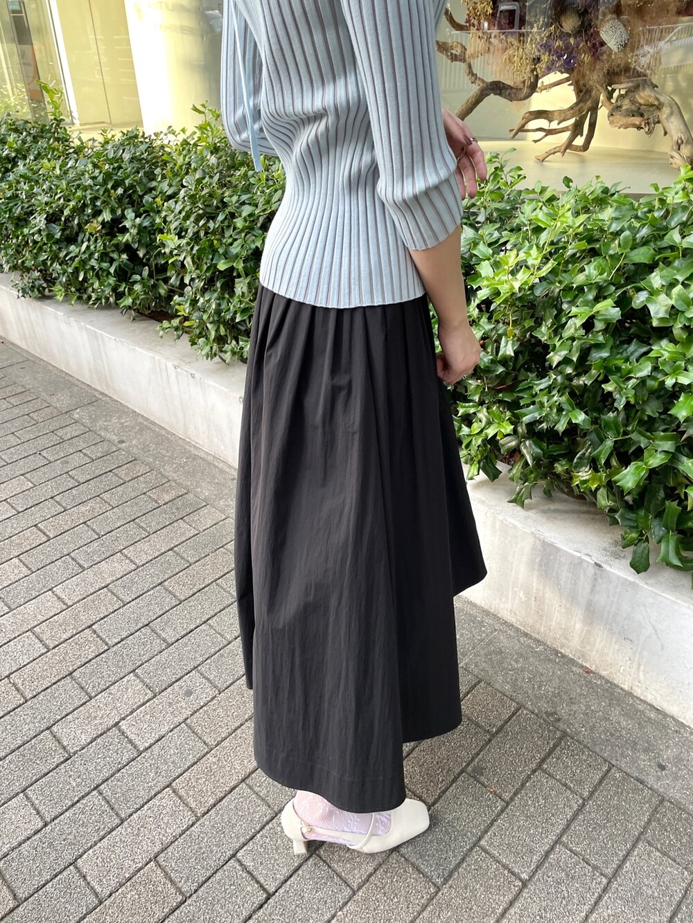 ブラック系のスカート、ブルー系のニット/セーター、ホワイト系のパンプスを着用したレディースの春コーディネートの6枚目の写真