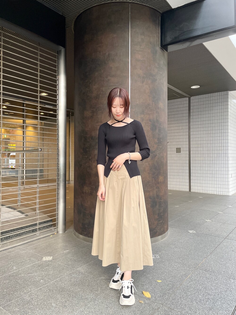 ブラック系のスニーカー、ブラック系のニット/セーター、ベージュ系のスカートを着用したレディースの春コーディネートの2枚目の写真
