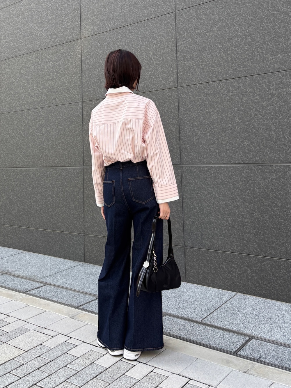 ピンク系のシャツ/ブラウス、ブルー系のデニムパンツ、ブラック系のハンドバッグを着用したレディースの春コーディネートの3枚目の写真