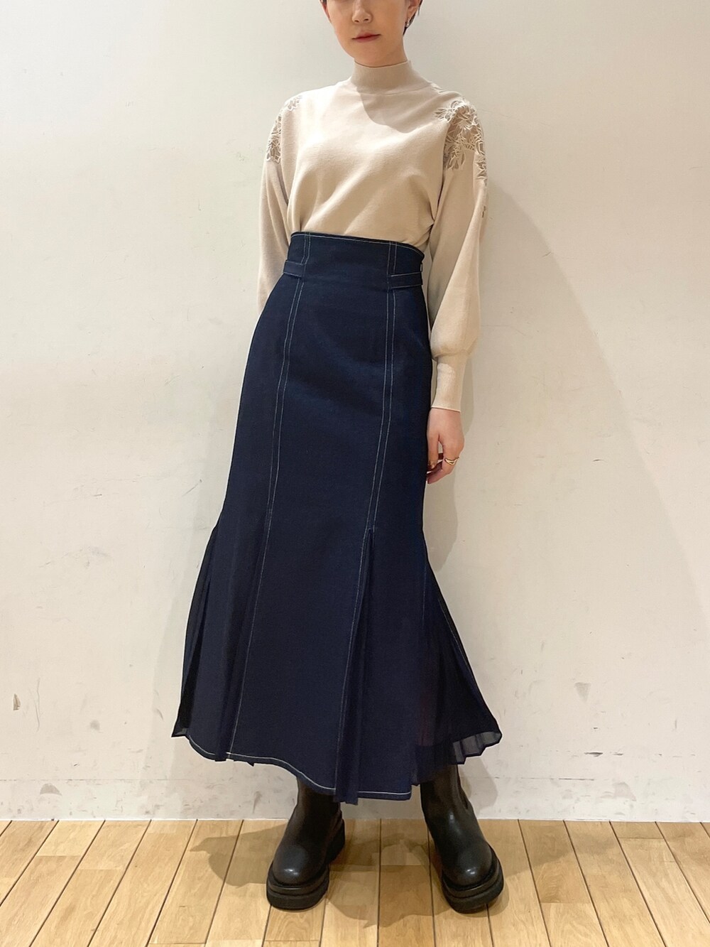 ホワイト系のニット/セーター、ブルー系のスカート、ブラック系のブーツを着用したレディースの冬コーディネートの6枚目の写真