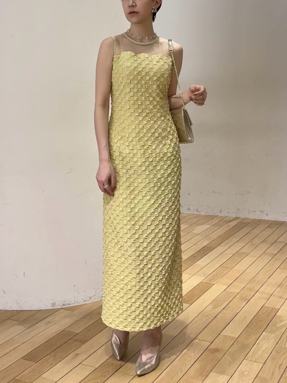 イエロー系のドレス、ゴールド系のパンプス、ゴールド系のクラッチバッグを着用したレディースの春コーディネートの6枚目の写真