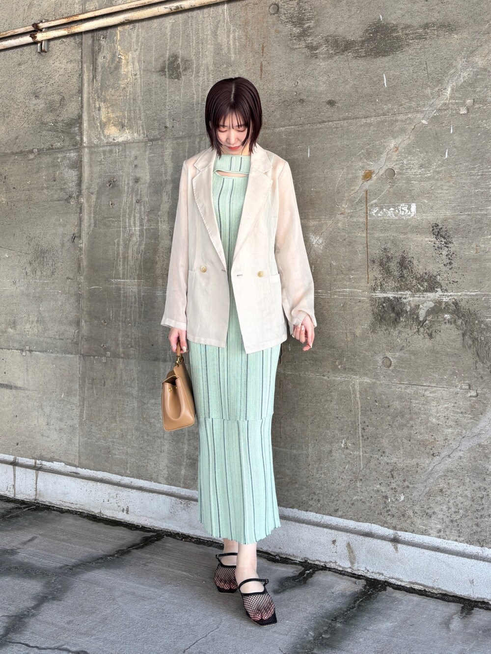 グリーン系のワンピース、ホワイト系のテーラードジャケット、ブラック系のサンダルを着用したレディースの春コーディネートの2枚目の写真