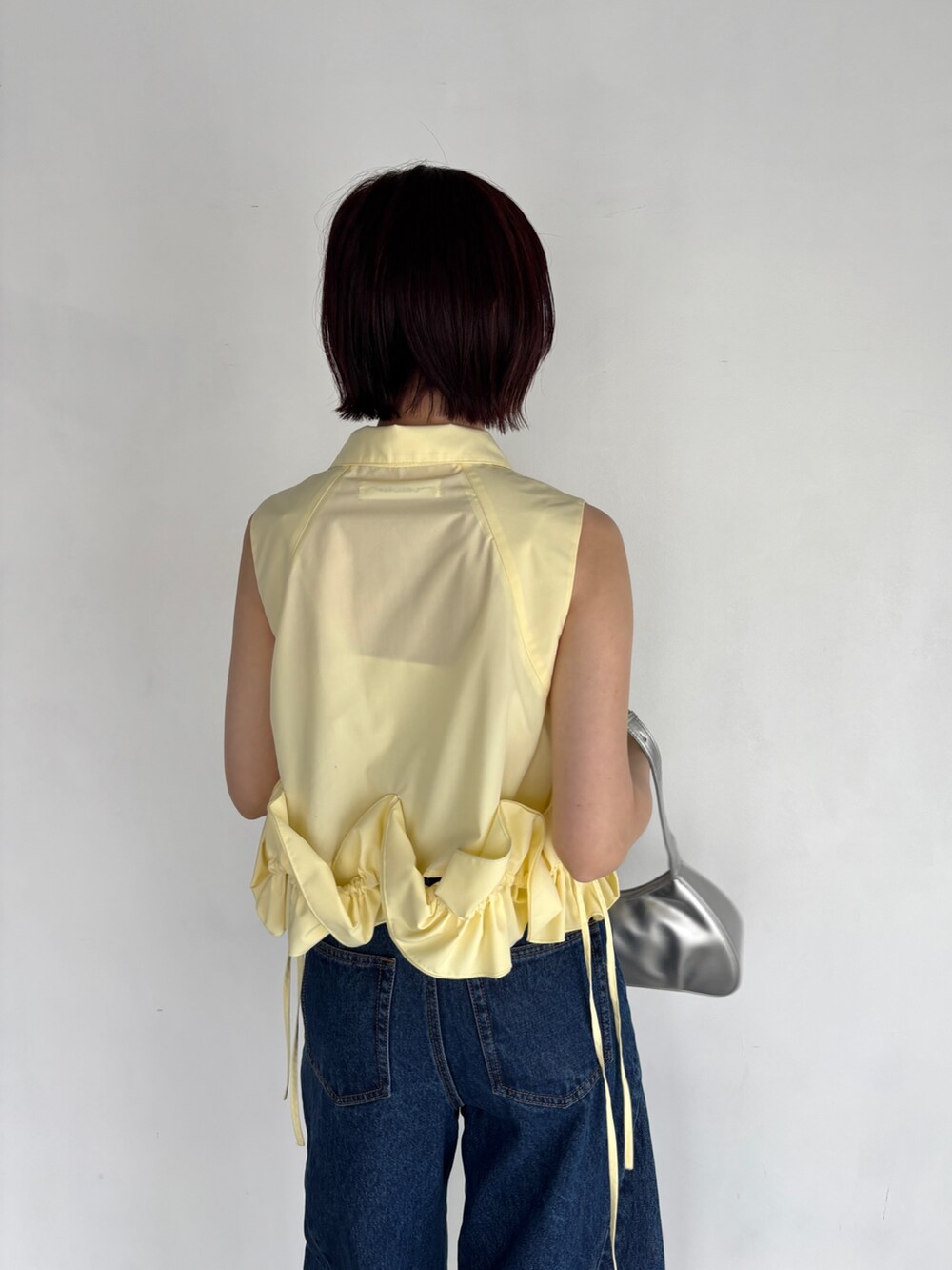 ブルー系のデニムパンツ、イエロー系のシャツ/ブラウス、シルバー系のハンドバッグを着用したレディースの夏コーディネートの5枚目の写真