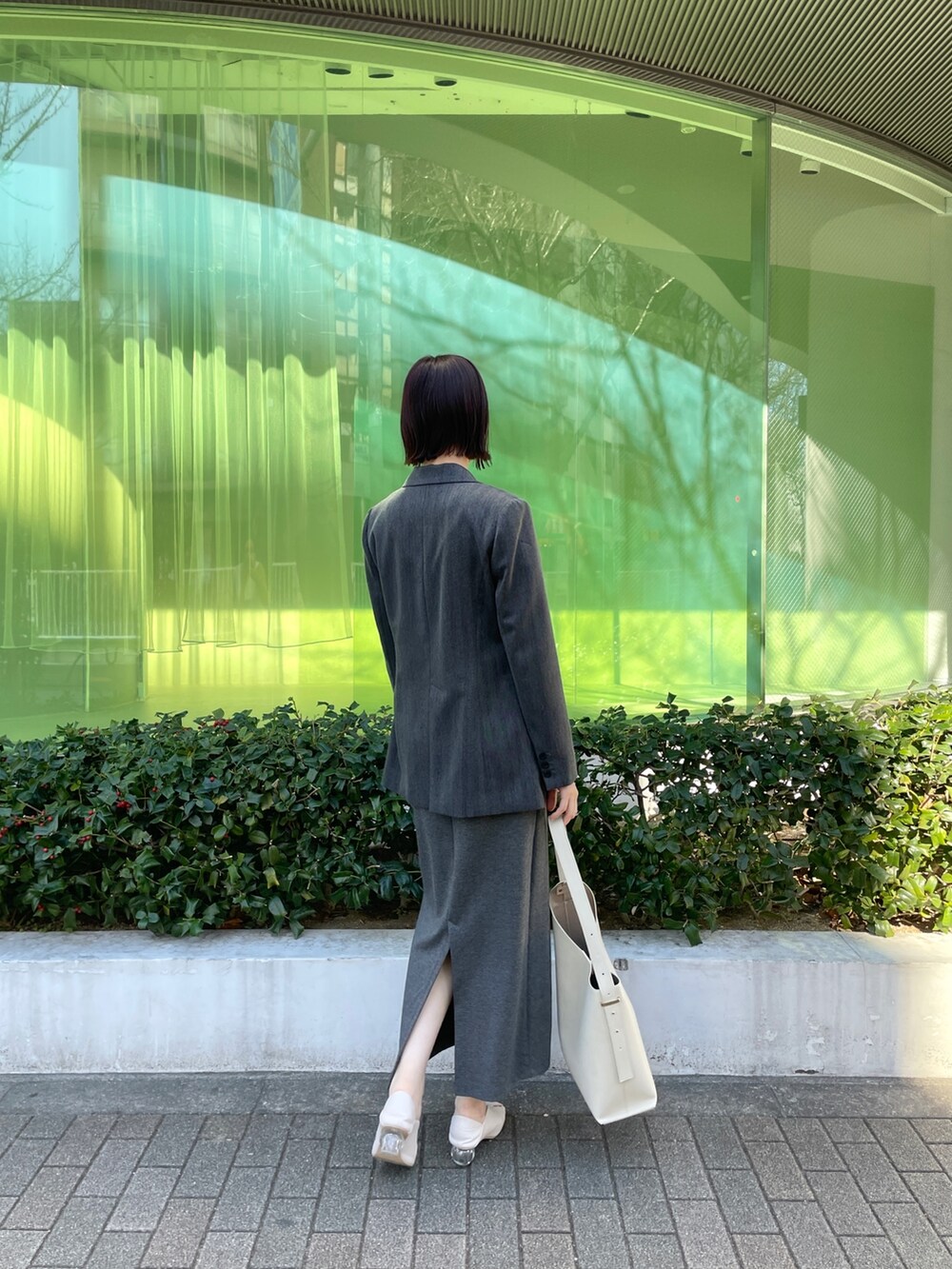 ホワイト系のパンプス、ホワイト系のショルダーバッグ、グレー系のワンピースを着用したレディースの冬コーディネートの5枚目の写真