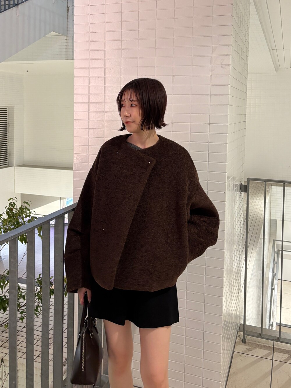 グレー系のニット/セーター、ブラウン系のブルゾン、ブラウン系のボストンバッグを着用したレディースの秋コーディネートの4枚目の写真