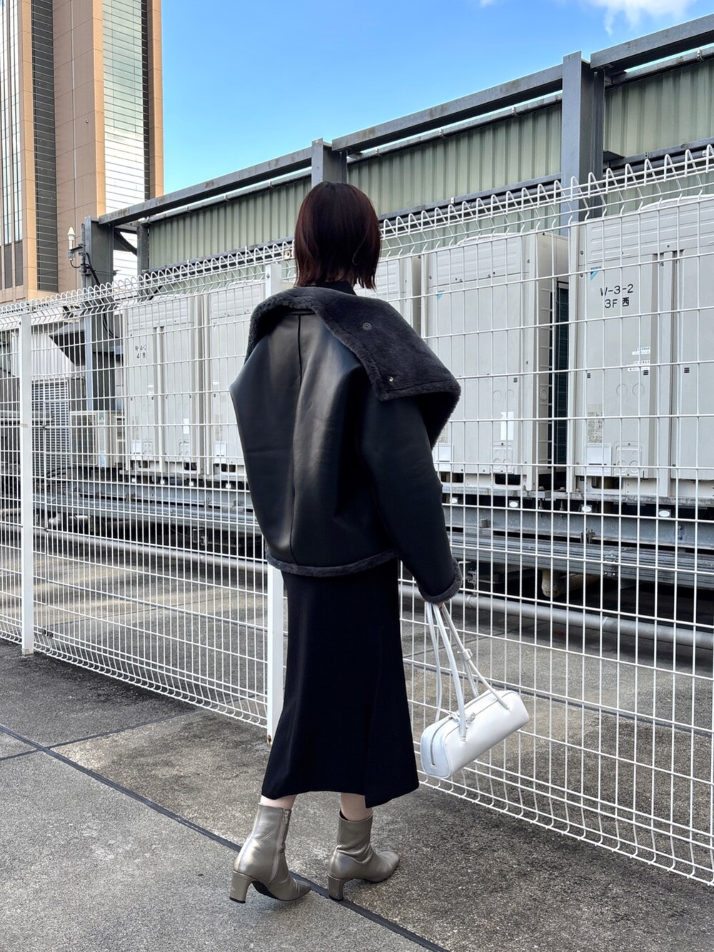 ブラック系のニット/セーター、ブラック系のスカート、グレー系のムートンコートを着用したレディースの冬コーディネートの6枚目の写真