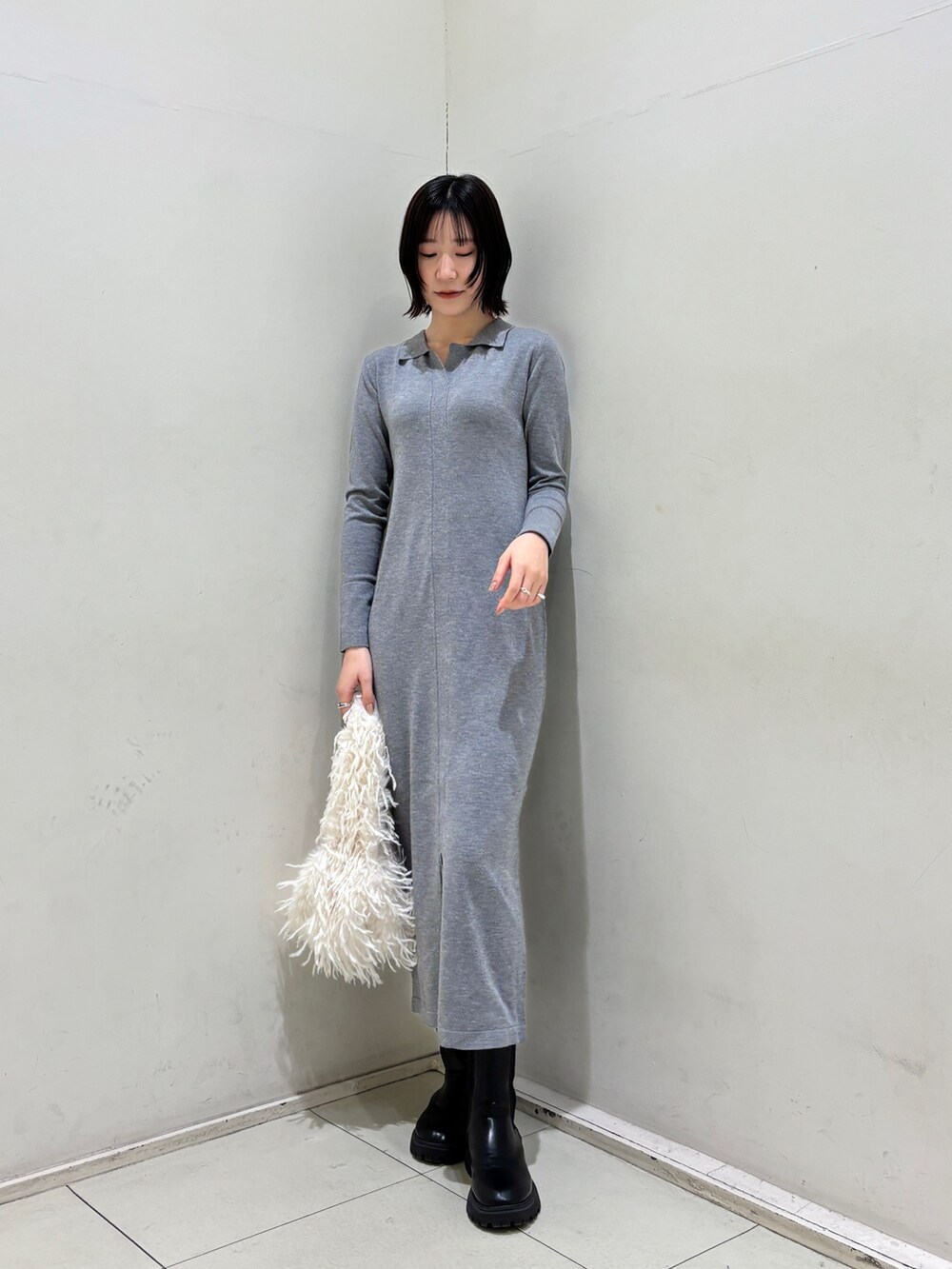 グレー系のワンピース、ホワイト系のハンドバッグを着用したレディースの冬コーディネートの2枚目の写真