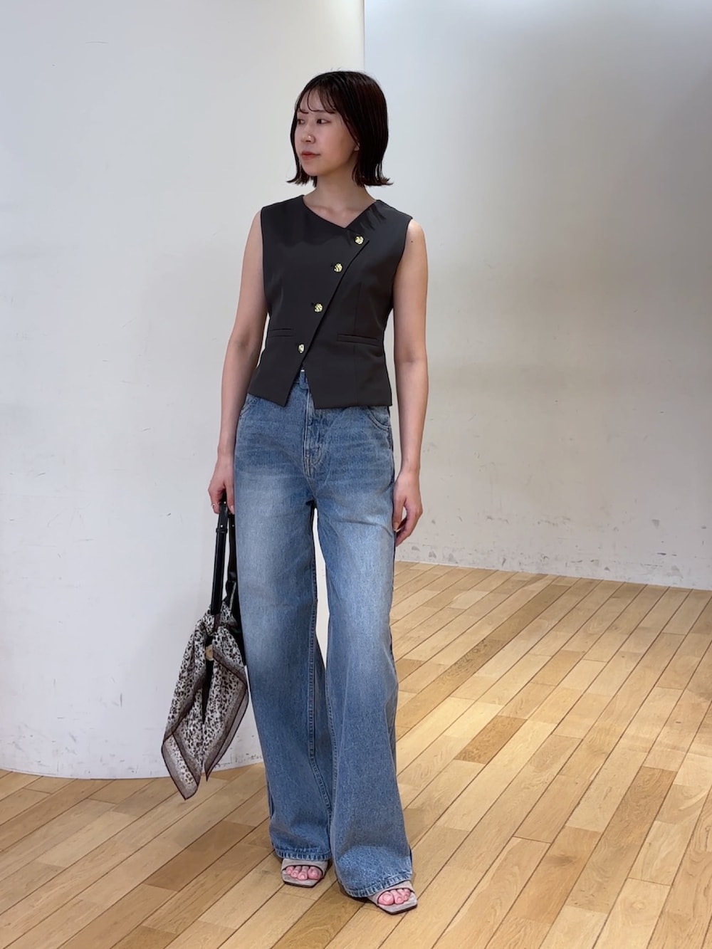 グレー系のワンピース、ブルー系のデニムパンツ、ブラック系のハンドバッグを着用したレディースの夏コーディネートの2枚目の写真