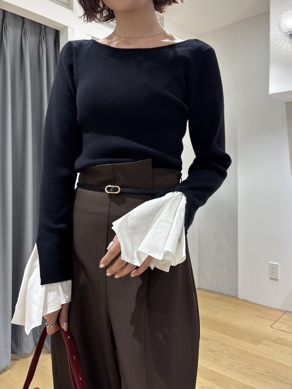 ブラック系のニット/セーター、ブラウン系のその他パンツ、レッド系のハンドバッグを着用したレディースの秋コーディネートの4枚目の写真