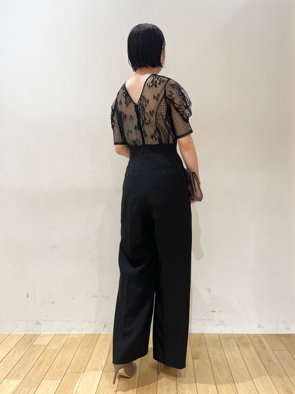 シルバー系のハンドバッグ、シルバー系のパンプス、ブラック系のパンツドレスを着用したレディースの夏コーディネートの5枚目の写真