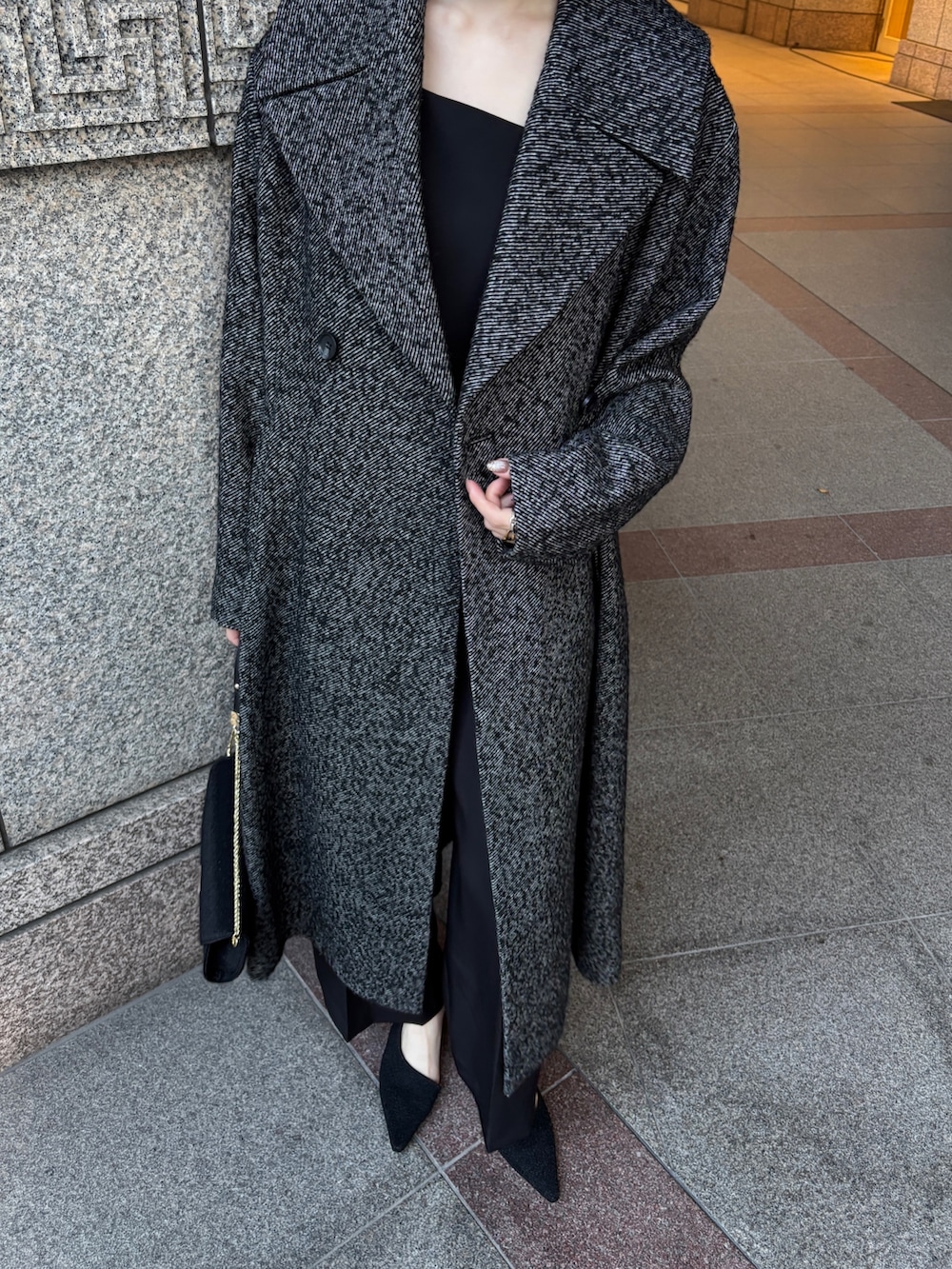 ブラック系のドレス、ブラック系のチェスターコート、ブラック系のハンドバッグを着用したレディースの冬コーディネートの6枚目の写真