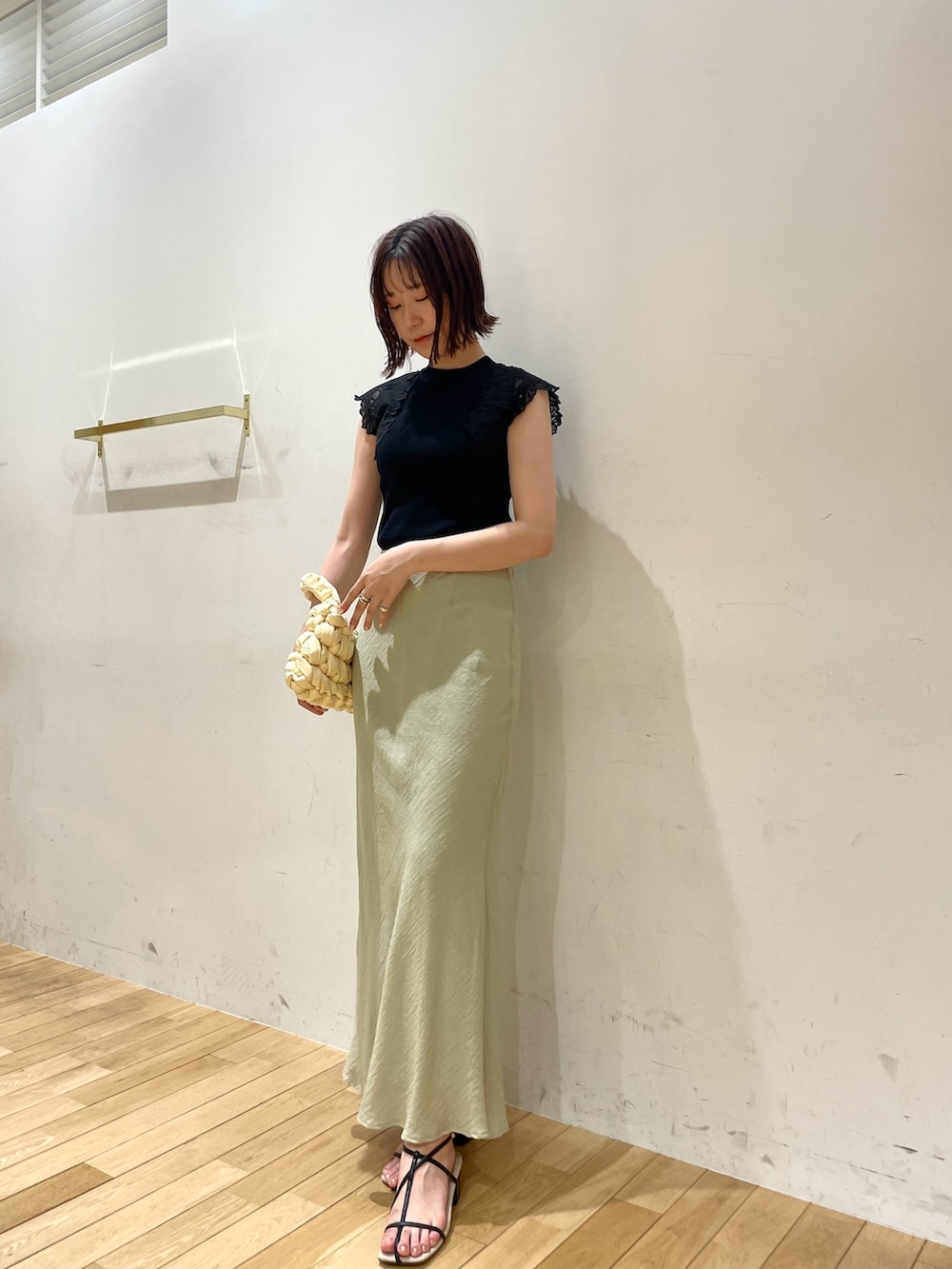 ベージュ系のハンドバッグ、ブラック系のサンダル、グリーン系のスカートを着用したレディースの夏コーディネートの3枚目の写真