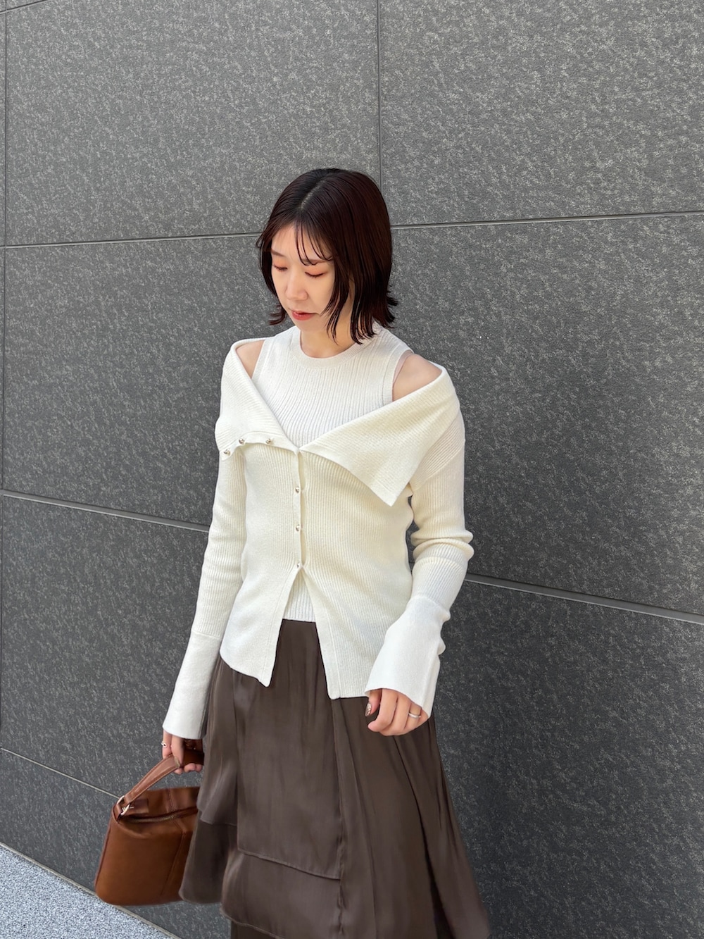 ブラウン系のスカート、イエロー系のハンドバッグ、ベージュ系のブーツを着用したレディースの冬コーディネートの3枚目の写真