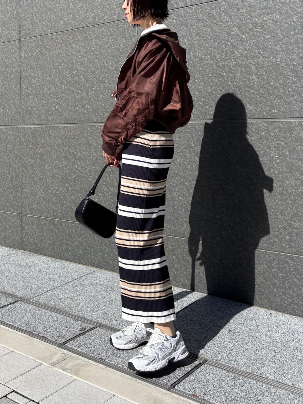 ベージュ系のワンピース、ブラック系のハンドバッグ、ブラウン系のブルゾンを着用したレディースの春コーディネートの3枚目の写真