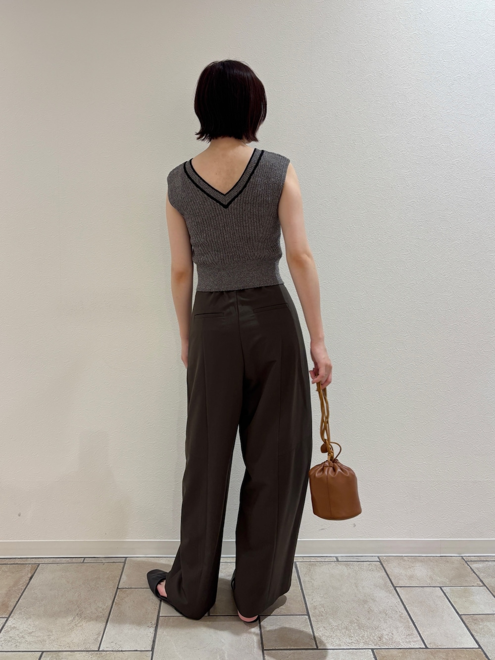 ブラウン系のその他パンツ、グレー系のニット/セーター、イエロー系のハンドバッグを着用したレディースの夏コーディネートの3枚目の写真