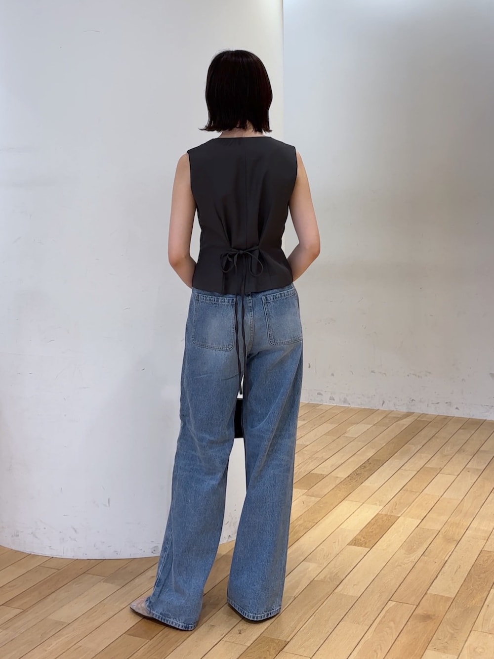 グレー系のワンピース、ブルー系のデニムパンツ、ブラック系のハンドバッグを着用したレディースの夏コーディネートの4枚目の写真