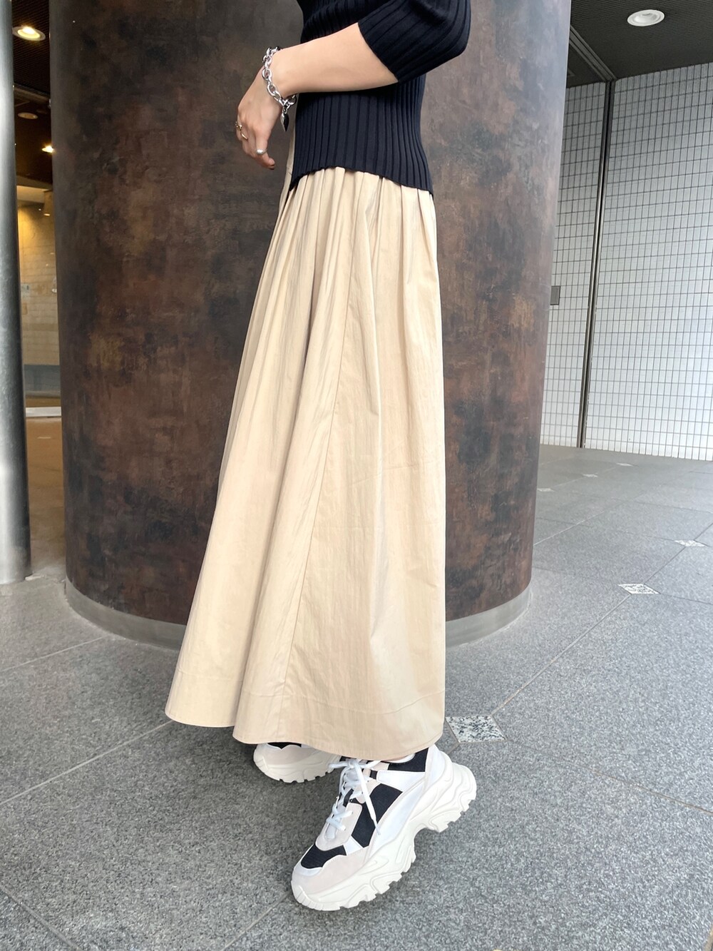 ブラック系のスニーカー、ブラック系のニット/セーター、ベージュ系のスカートを着用したレディースの春コーディネートの6枚目の写真