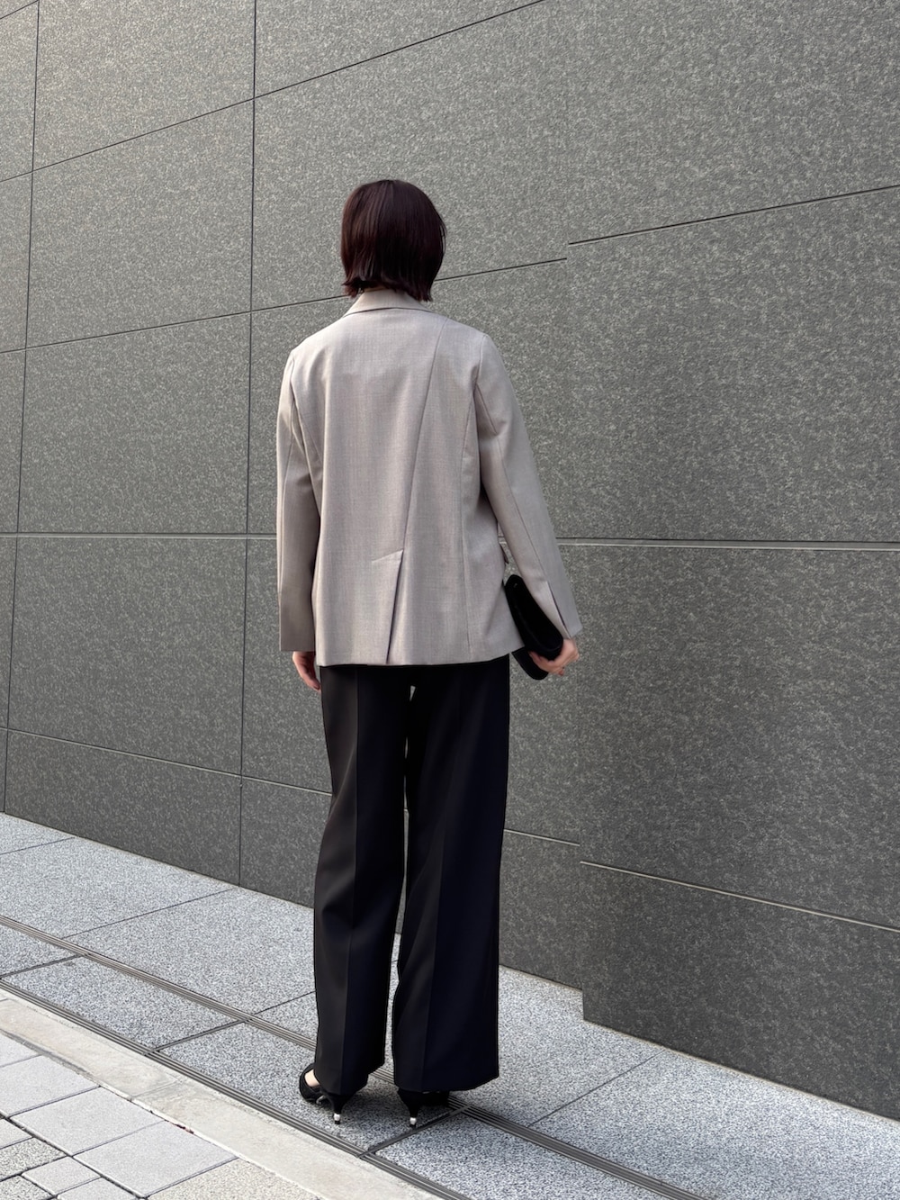 ブラック系のドレス、ブラック系のパンプス、ブラック系のハンドバッグを着用したレディースの冬コーディネートの6枚目の写真