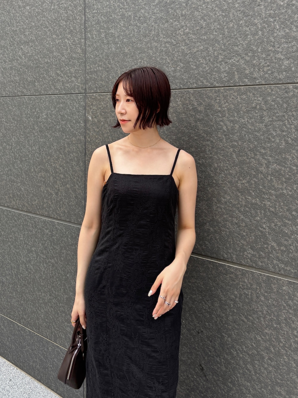 ブラック系のワンピース、ブラウン系のパンプス、ブラウン系のボストンバッグを着用したレディースの夏コーディネートの5枚目の写真