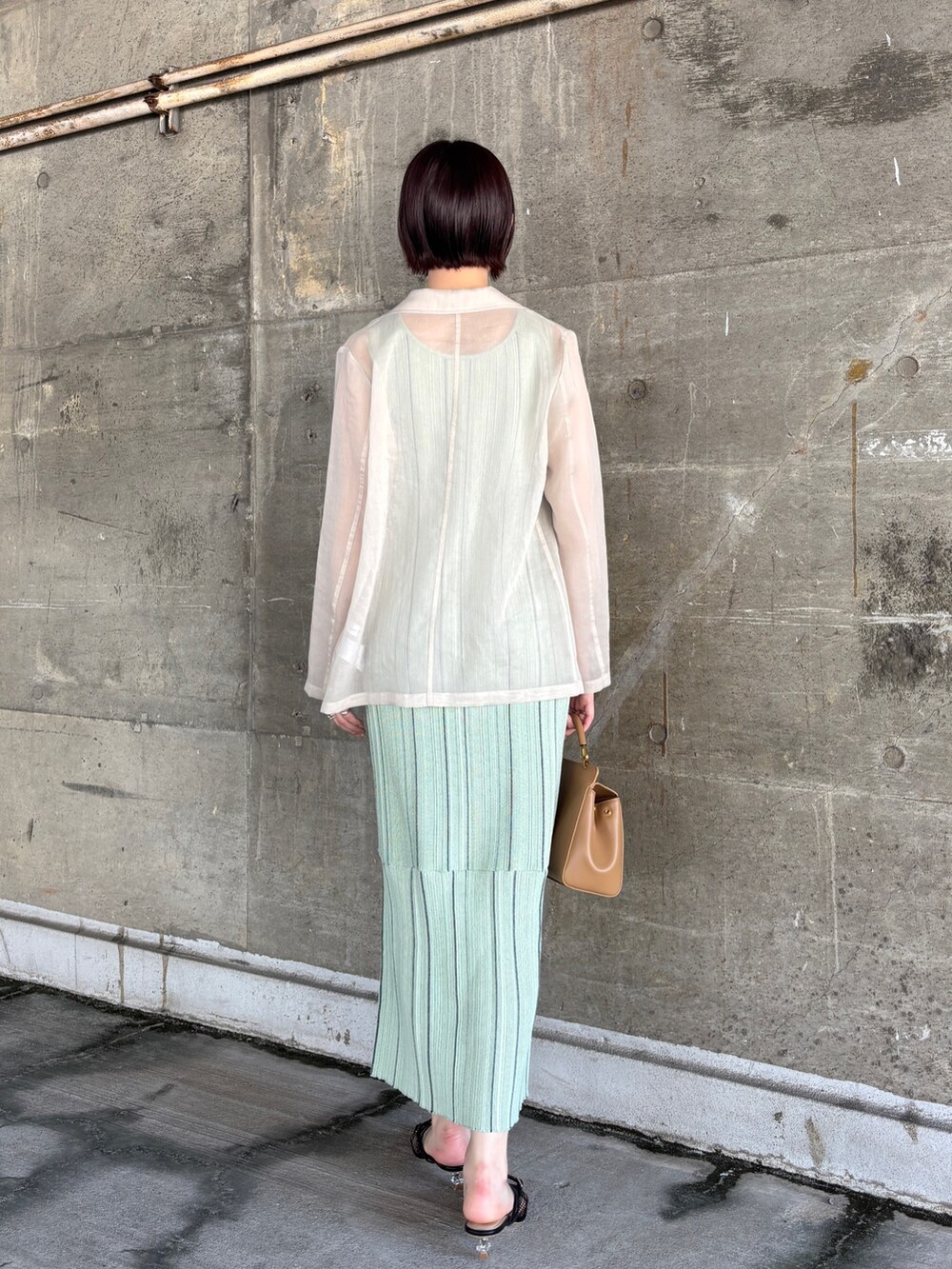 グリーン系のワンピース、ホワイト系のテーラードジャケット、ブラック系のサンダルを着用したレディースの春コーディネートの4枚目の写真