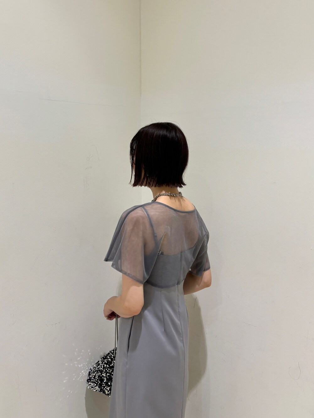 シルバー系のハンドバッグ、ブラック系のパンプス、パープル系のドレスを着用したレディースの夏コーディネートの5枚目の写真