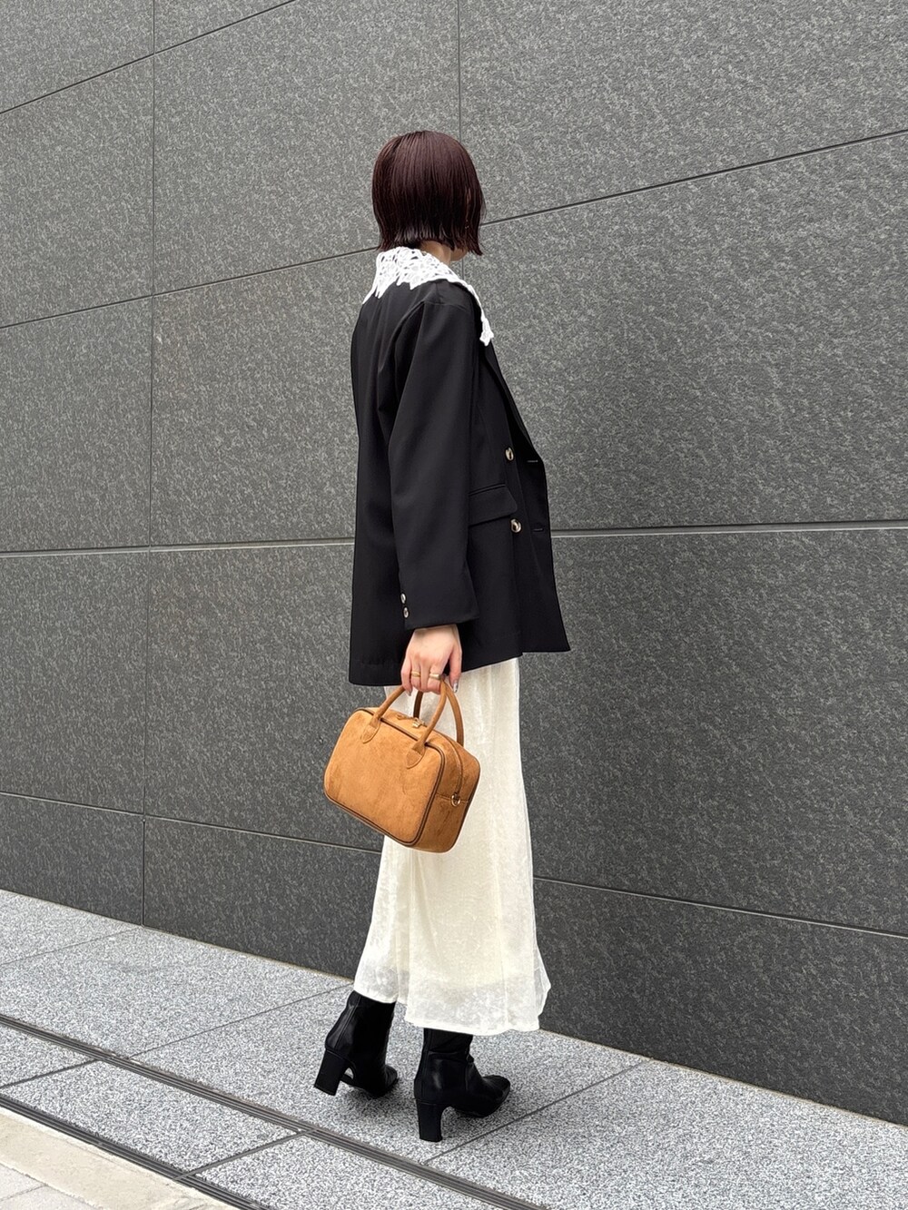 ホワイト系のスカート、イエロー系のハンドバッグ、ブラック系のブーツを着用したレディースの秋コーディネートの4枚目の写真