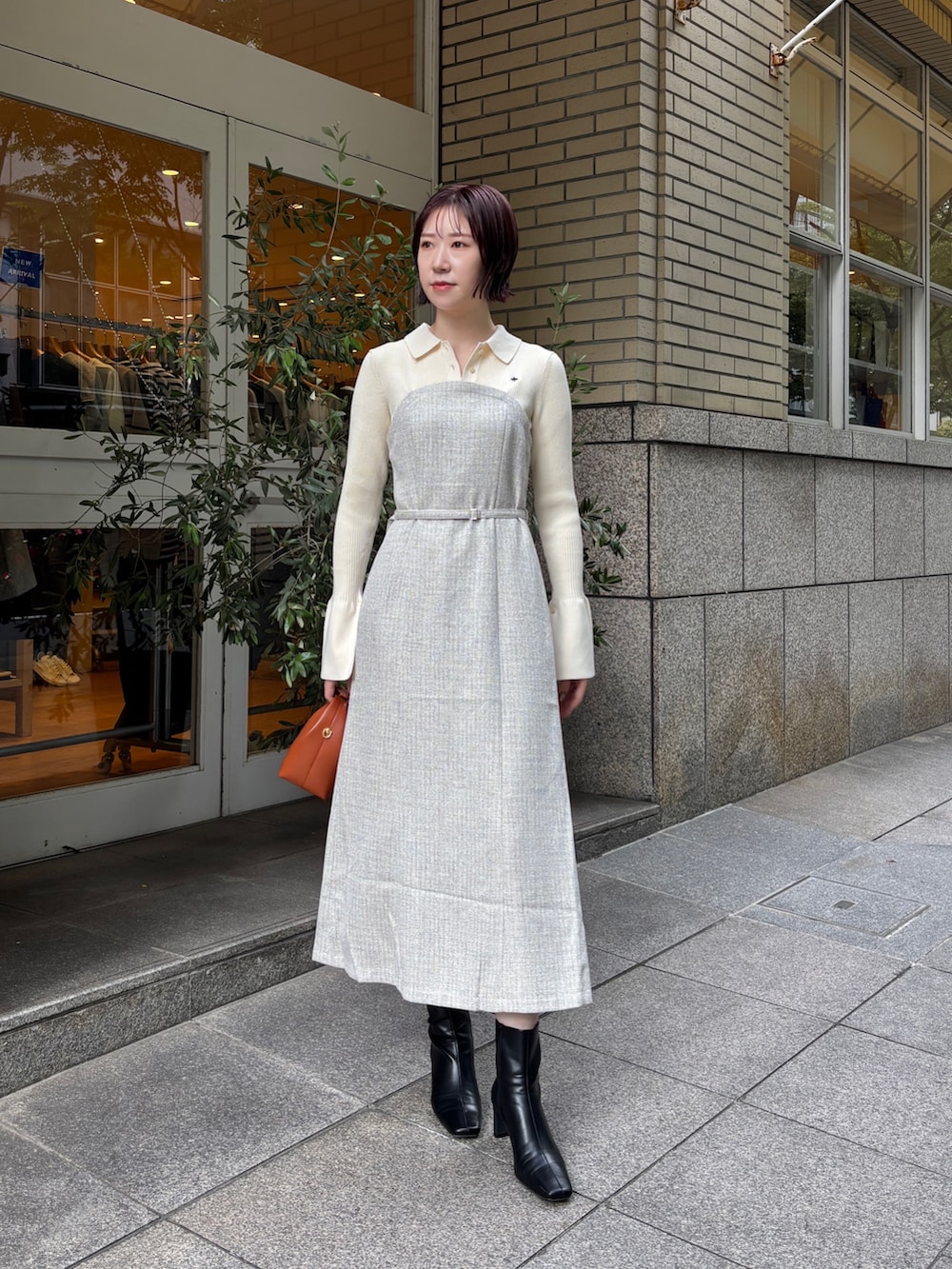 ホワイト系のワンピース、ブラウン系のハンドバッグ、ブラック系のブーツを着用したレディースの秋コーディネートの2枚目の写真