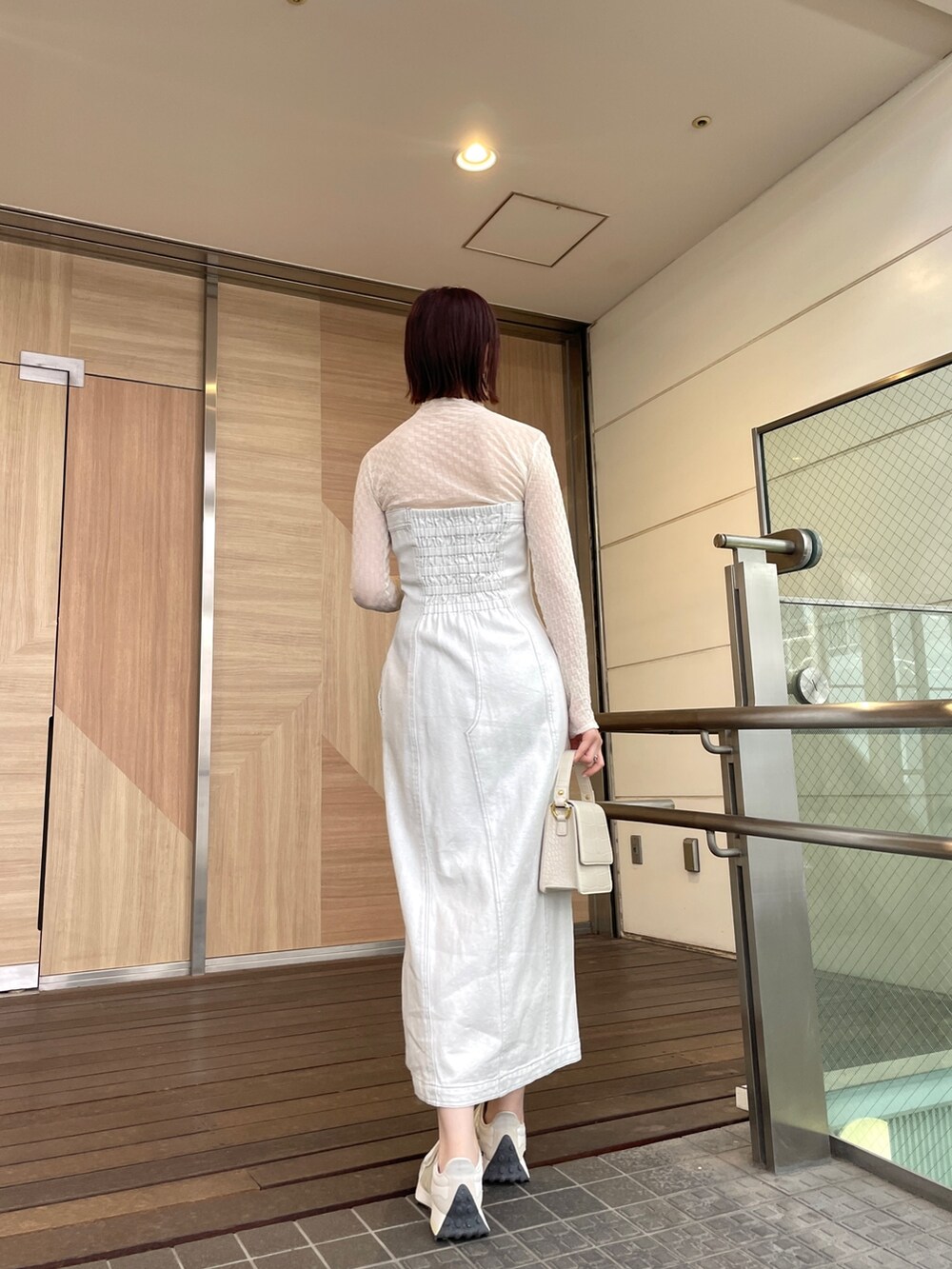 ホワイト系のショルダーバッグ、ホワイト系のワンピース、ブラック系のデニムジャケットを着用したレディースの春コーディネートの4枚目の写真