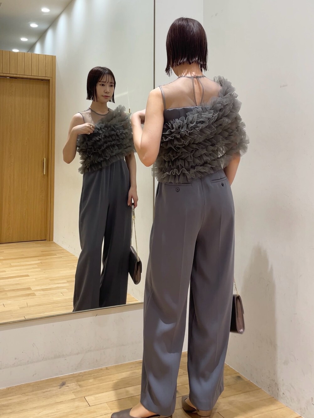 シルバー系のハンドバッグ、その他のパンプス、グレー系のパンツドレスを着用したレディースの冬コーディネートの5枚目の写真