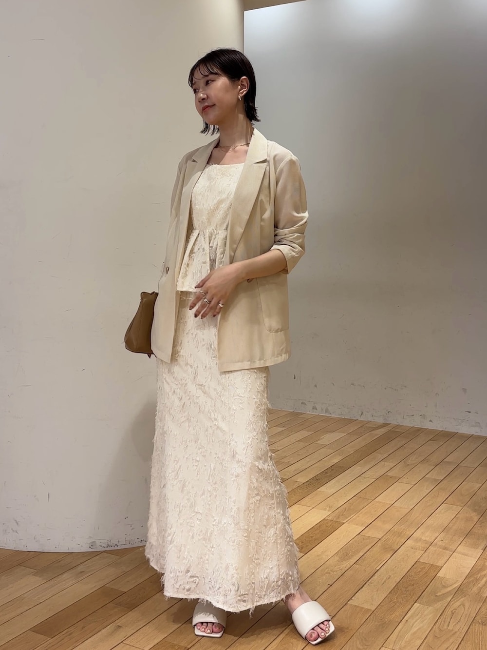 ホワイト系のスカート、ホワイト系のキャミソール、ホワイト系のテーラードジャケットを着用したレディースの夏コーディネートの2枚目の写真