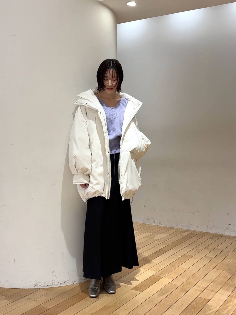 ブラック系のスカート、パープル系のニット/セーター、ホワイト系のダウンジャケット/コートを着用したレディースの冬コーディネートの2枚目の写真