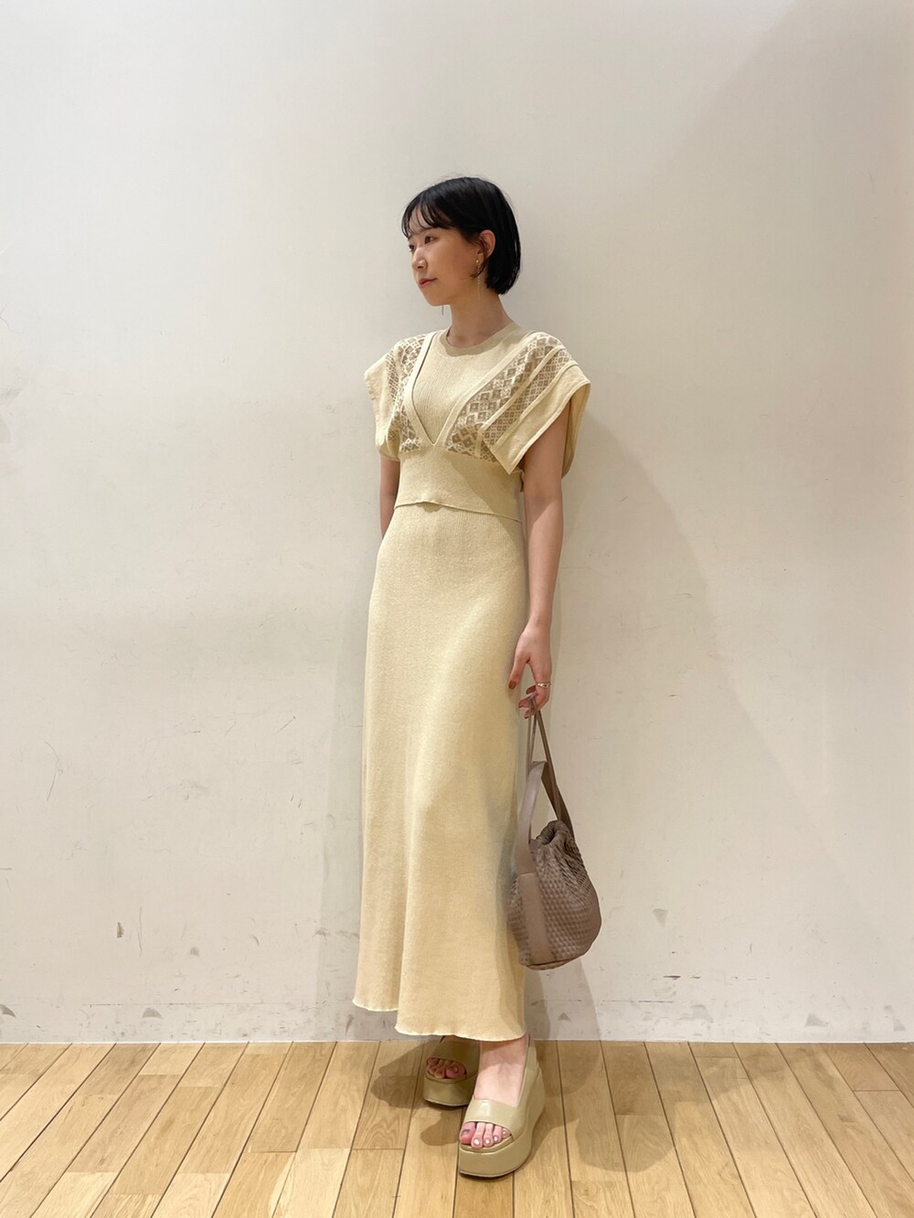 ベージュ系のワンピース、ブラウン系のハンドバッグ、ベージュ系のサンダルを着用したレディースの夏コーディネートの2枚目の写真
