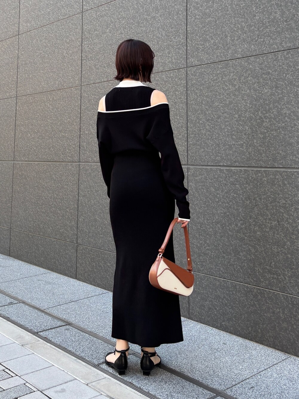 ブラック系のワンピース、ブラウン系のハンドバッグ、ブラック系のパンプスを着用したレディースの春コーディネートの3枚目の写真