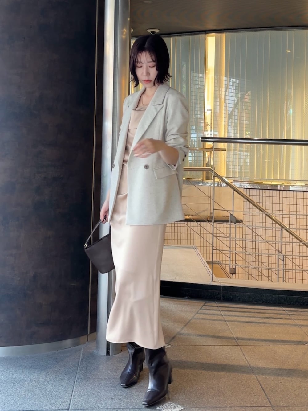 ホワイト系のテーラードジャケット、ブラウン系のハンドバッグ、ブラウン系のブーツを着用したレディースの冬コーディネートの2枚目の写真