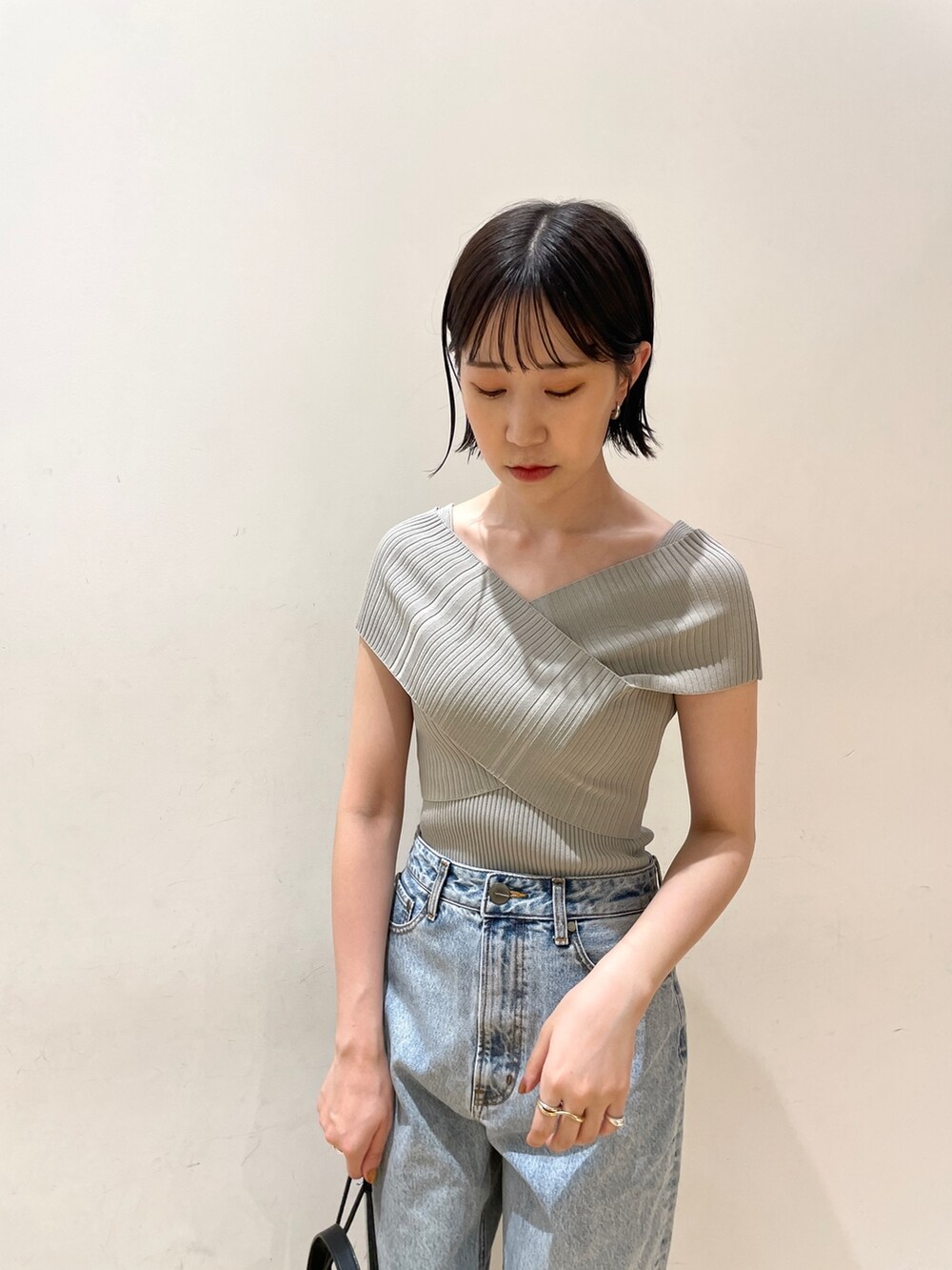 グリーン系のニット/セーター、ブルー系のデニムパンツ、ブラック系のハンドバッグを着用したレディースの夏コーディネートの5枚目の写真