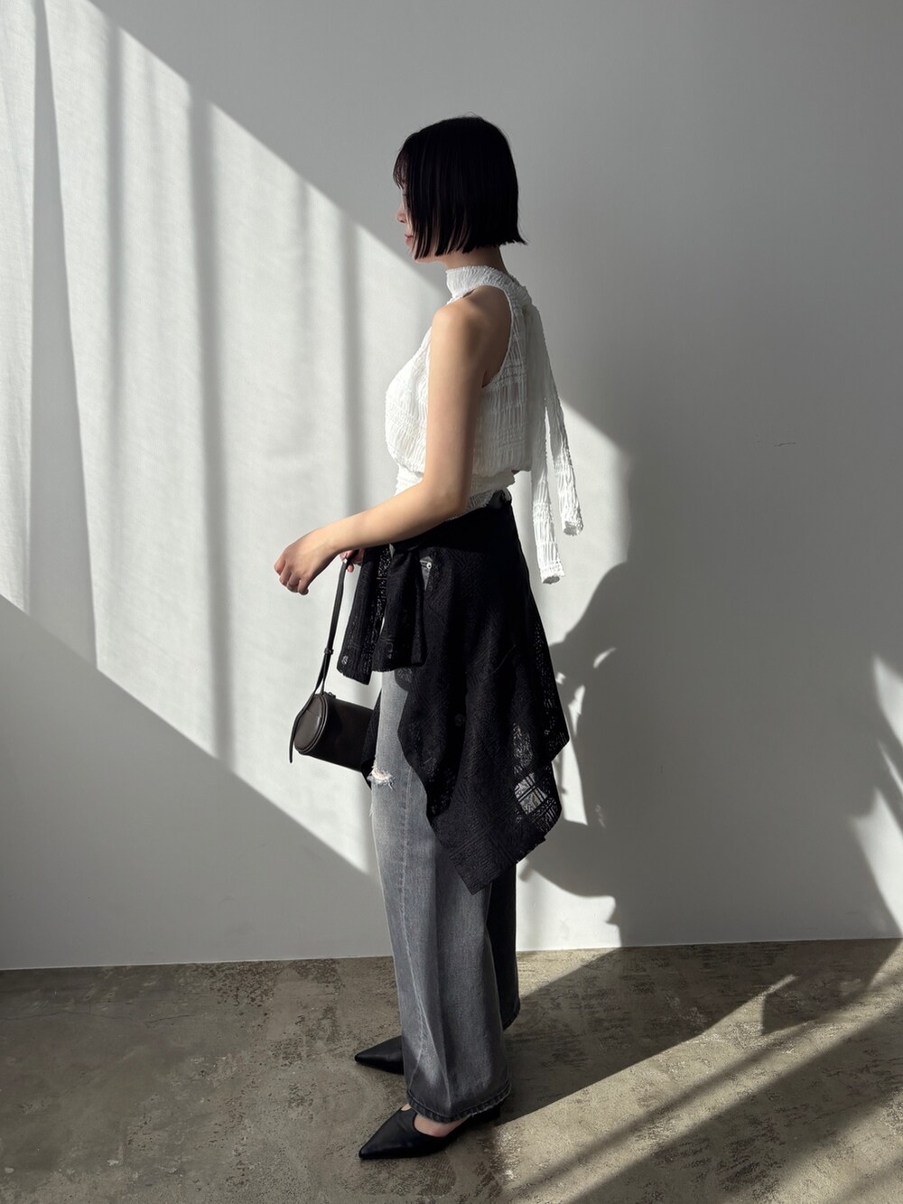 グレー系のデニムパンツ、ブラック系のパンプス、ブラック系のテーラードジャケットを着用したレディースの春コーディネートの3枚目の写真