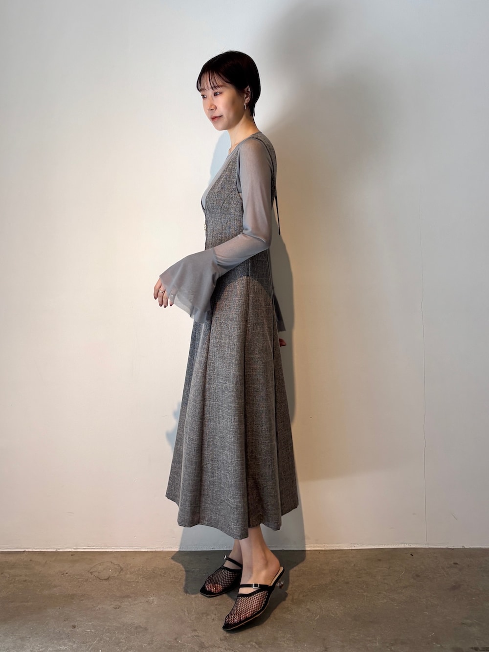 グレー系のジャンパースカート、ブルー系のTシャツ/カットソー、ブラック系のサンダルを着用したレディースの春コーディネートの3枚目の写真