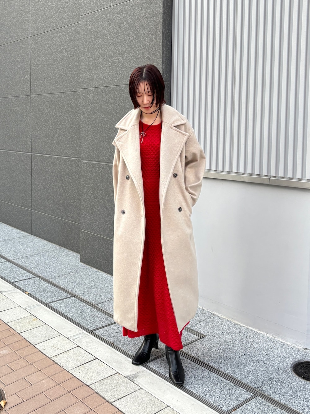 レッド系のワンピース、ホワイト系のチェスターコートを着用したレディースの冬コーディネートの3枚目の写真
