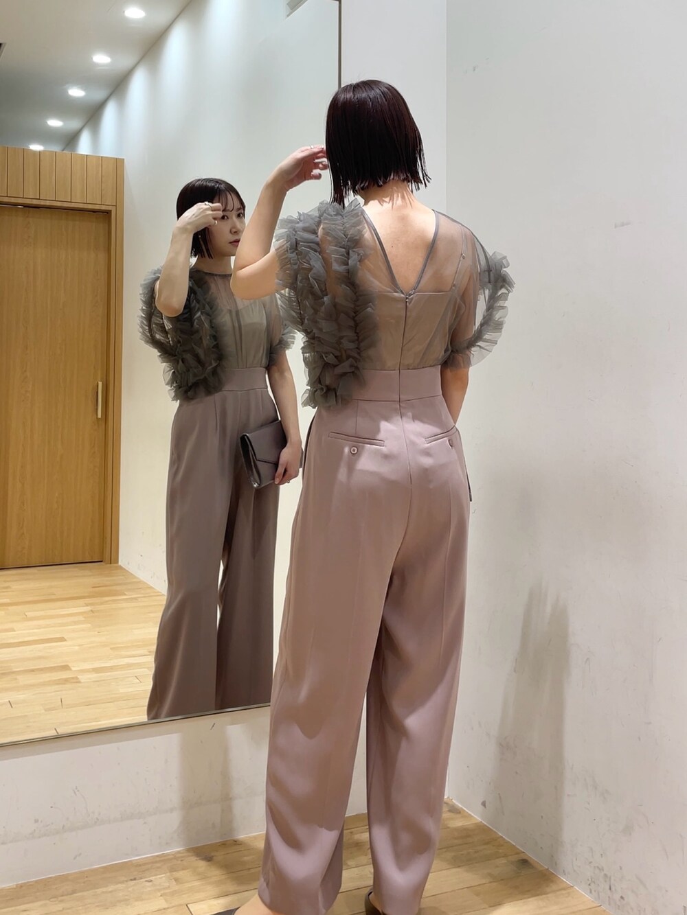 シルバー系のハンドバッグ、ピンク系のパンツドレス、その他のパンプスを着用したレディースの冬コーディネートの3枚目の写真