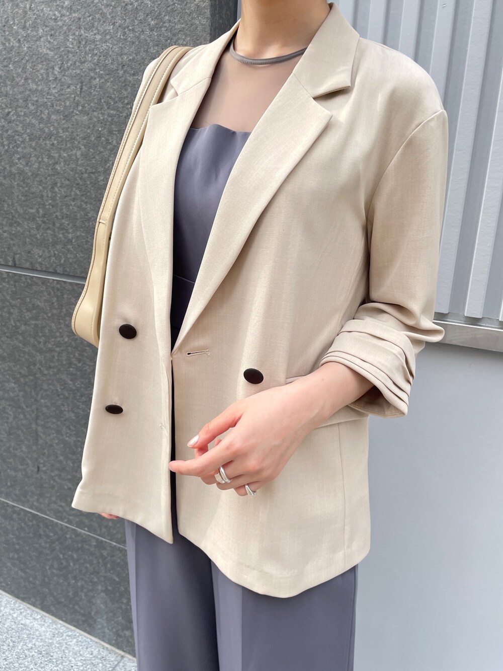 グレー系のパンツドレス、その他のパンプス、ベージュ系のテーラードジャケットを着用したレディースの春コーディネートの7枚目の写真