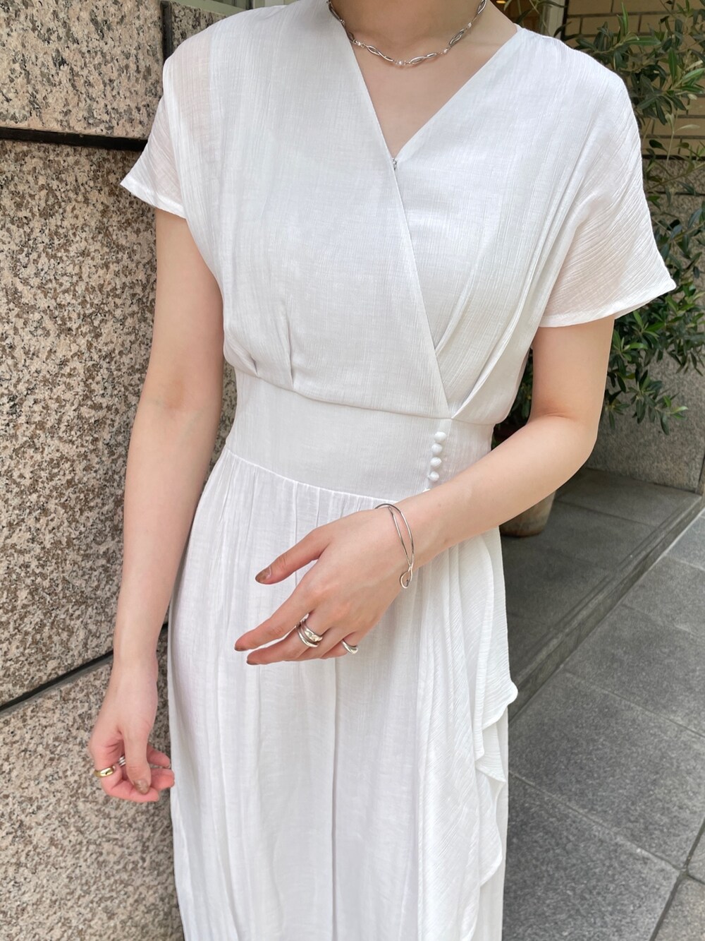 ブラウン系のショルダーバッグ、ホワイト系のワンピース、シルバー系のチョーカーを着用したレディースの夏コーディネートの6枚目の写真