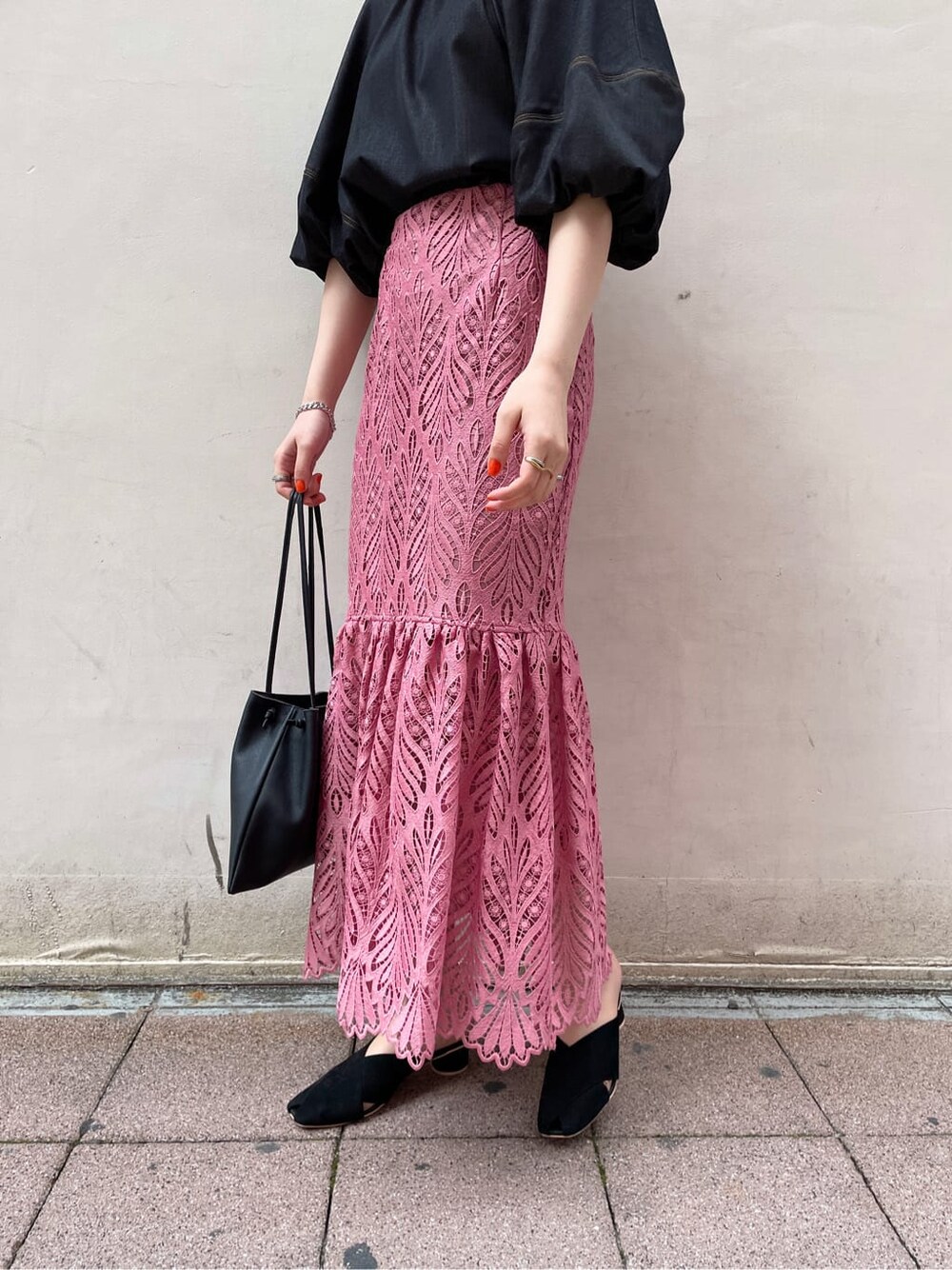 ブラック系のハンドバッグ、ブラック系のサンダル、ピンク系のスカートを着用したレディースの春コーディネートの4枚目の写真