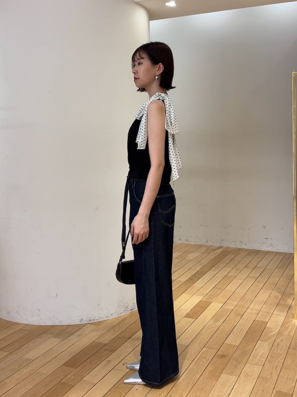 ブルー系のデニムパンツ、ブラック系のハンドバッグ、シルバー系のパンプスを着用したレディースの夏コーディネートの2枚目の写真