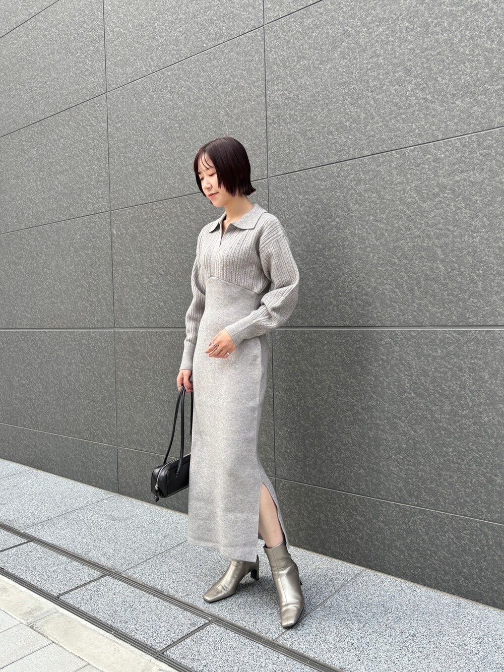 グレー系のワンピース、シルバー系のブーツ、ブラック系のショルダーバッグを着用したレディースの秋コーディネートの2枚目の写真