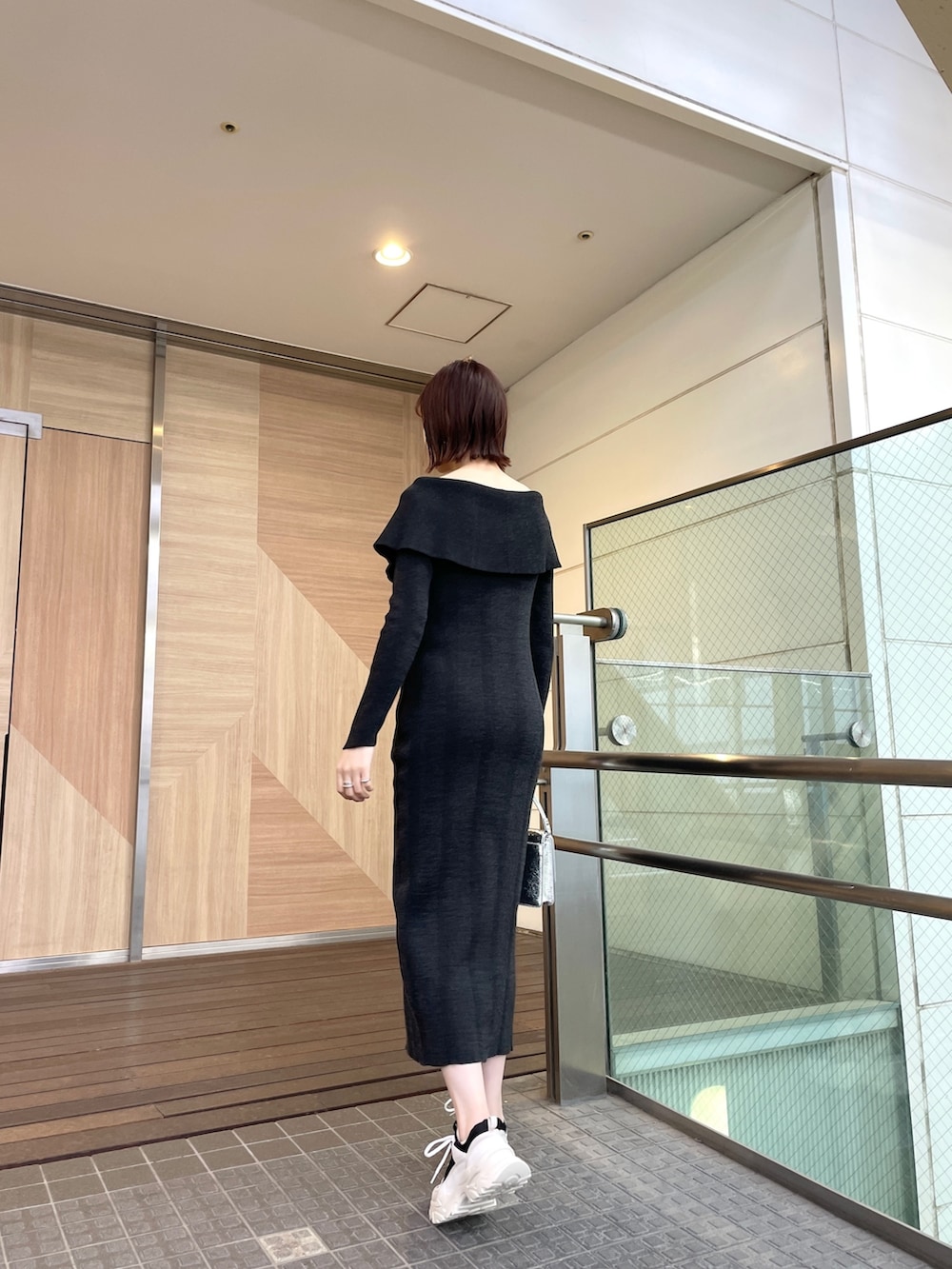 ブラック系のワンピース、ブラック系のスニーカー、シルバー系のショルダーバッグを着用したレディースの春コーディネートの4枚目の写真