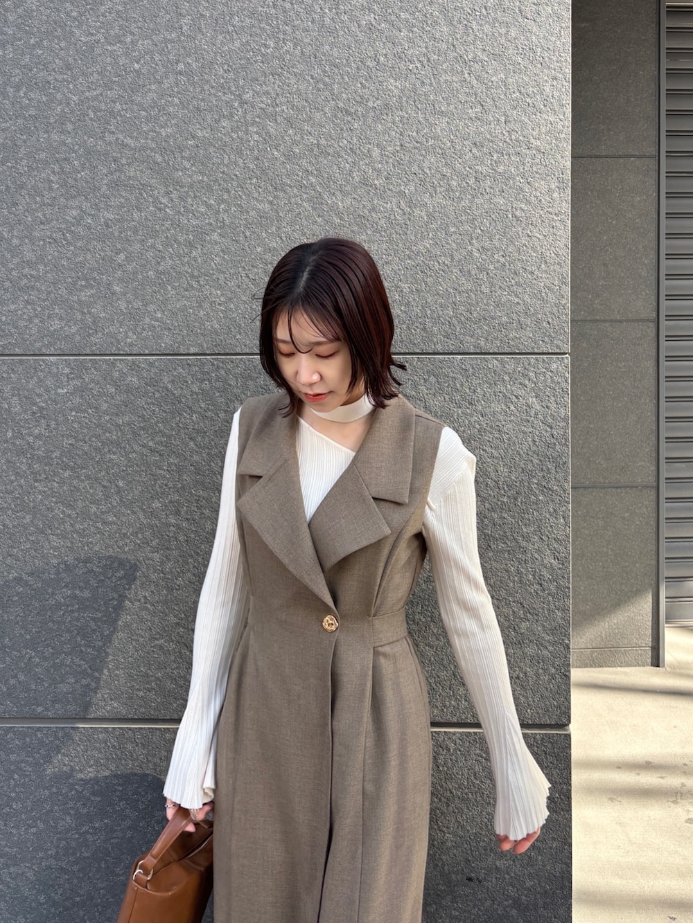 ブラウン系のワンピース、ホワイト系のニット/セーター、イエロー系のハンドバッグを着用したレディースの冬コーディネートの4枚目の写真