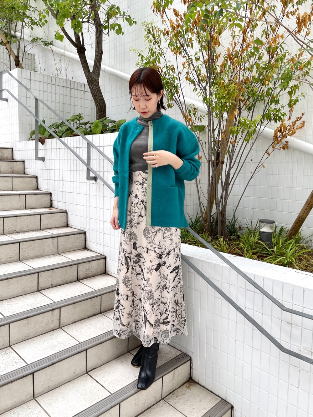 グレー系のTシャツ/カットソー、ホワイト系のスカート、ブラック系のブーツを着用したレディースの秋コーディネートの6枚目の写真