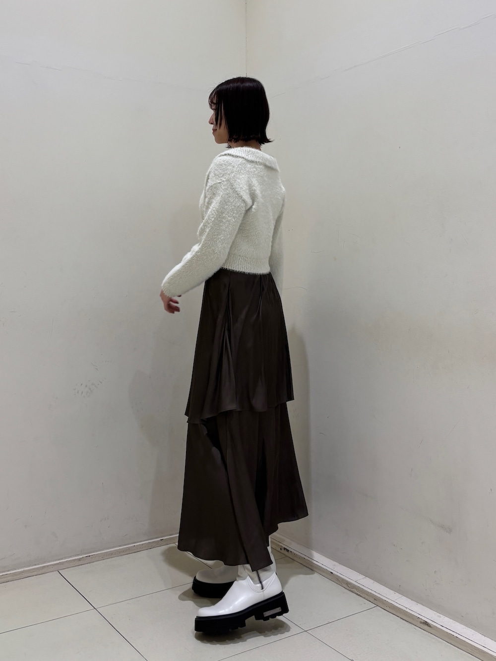 ブラウン系のスカート、ホワイト系のアンサンブルを着用したレディースの冬コーディネートの2枚目の写真